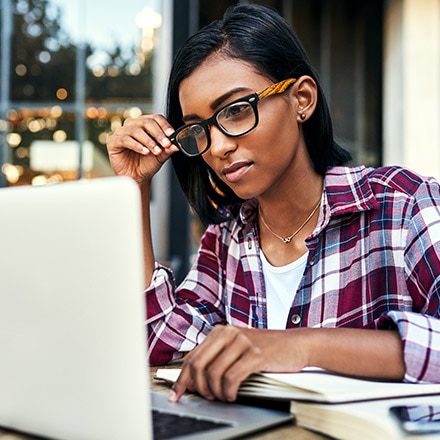 A person sitting by a window, researching certificate programs on a laptop.