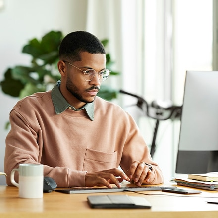 A man working on his desktop researching the types of graduate degrees