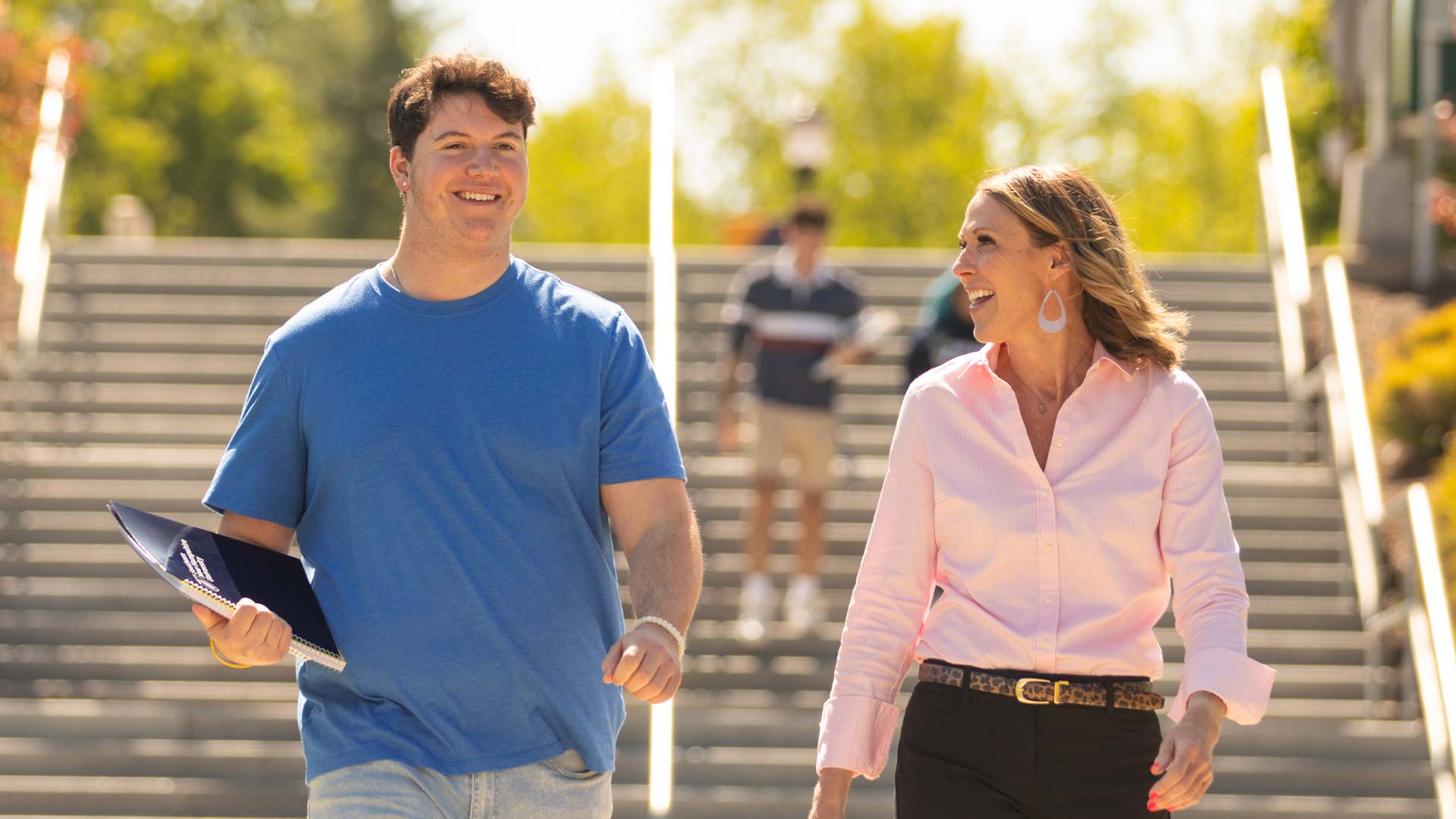 Two individuals climbing down the stairs while talking and smiling.
