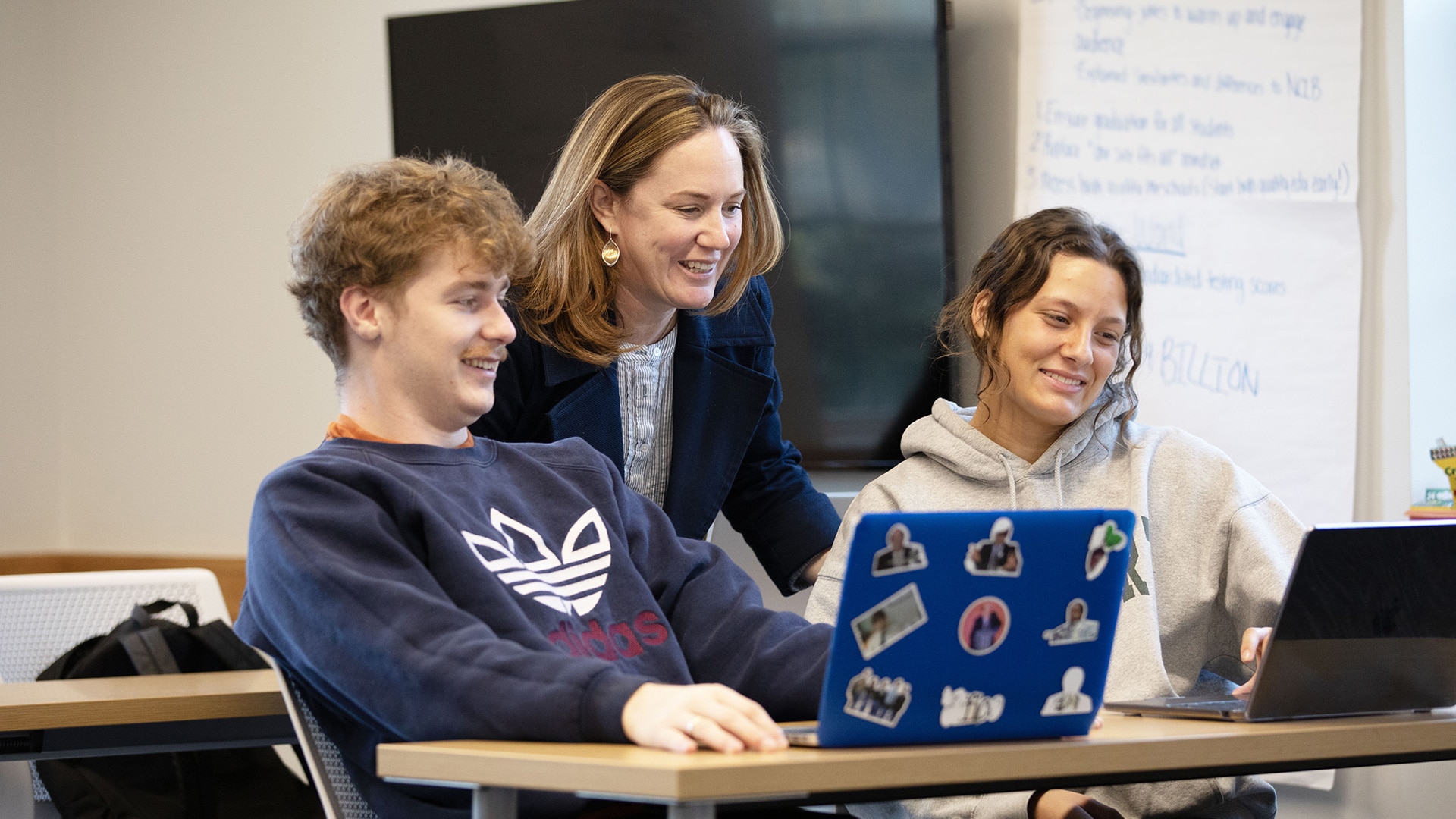 A group of two students studying and discussing with their teacher/professor.