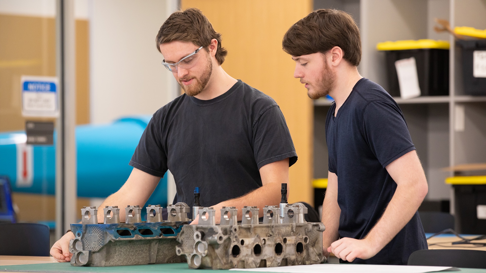 Two students inspecting some mechanical equipment.