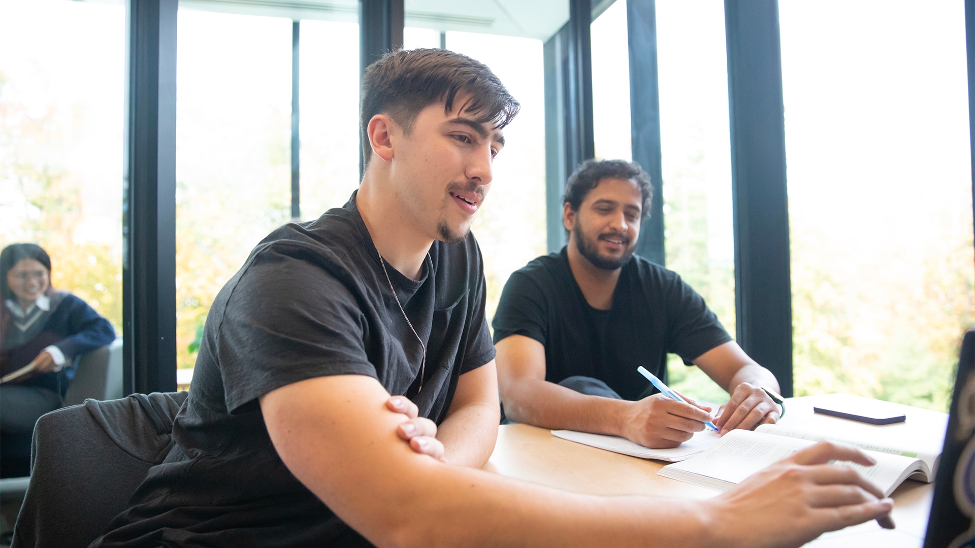 Two students studying together with laptop and books.