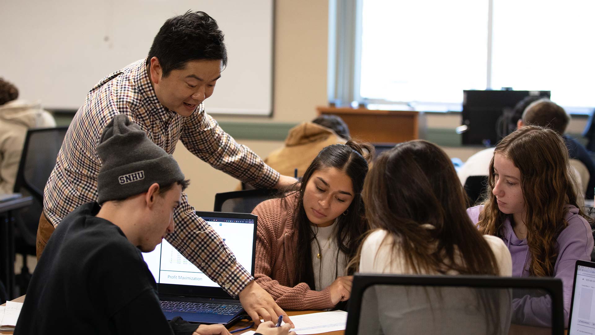 A professor discussing something from a sheet of paper with a group of four students.