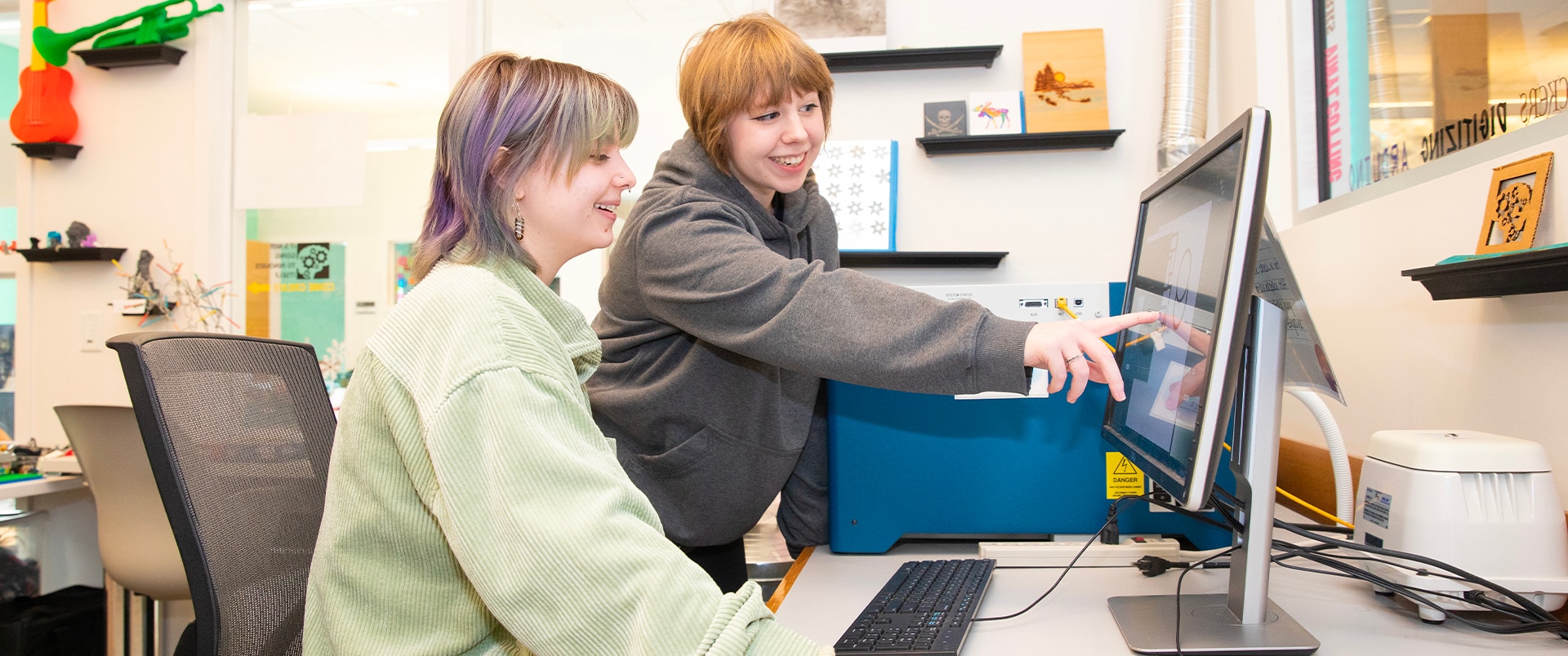 A group of two individuals smiling and looking at a computer screen.