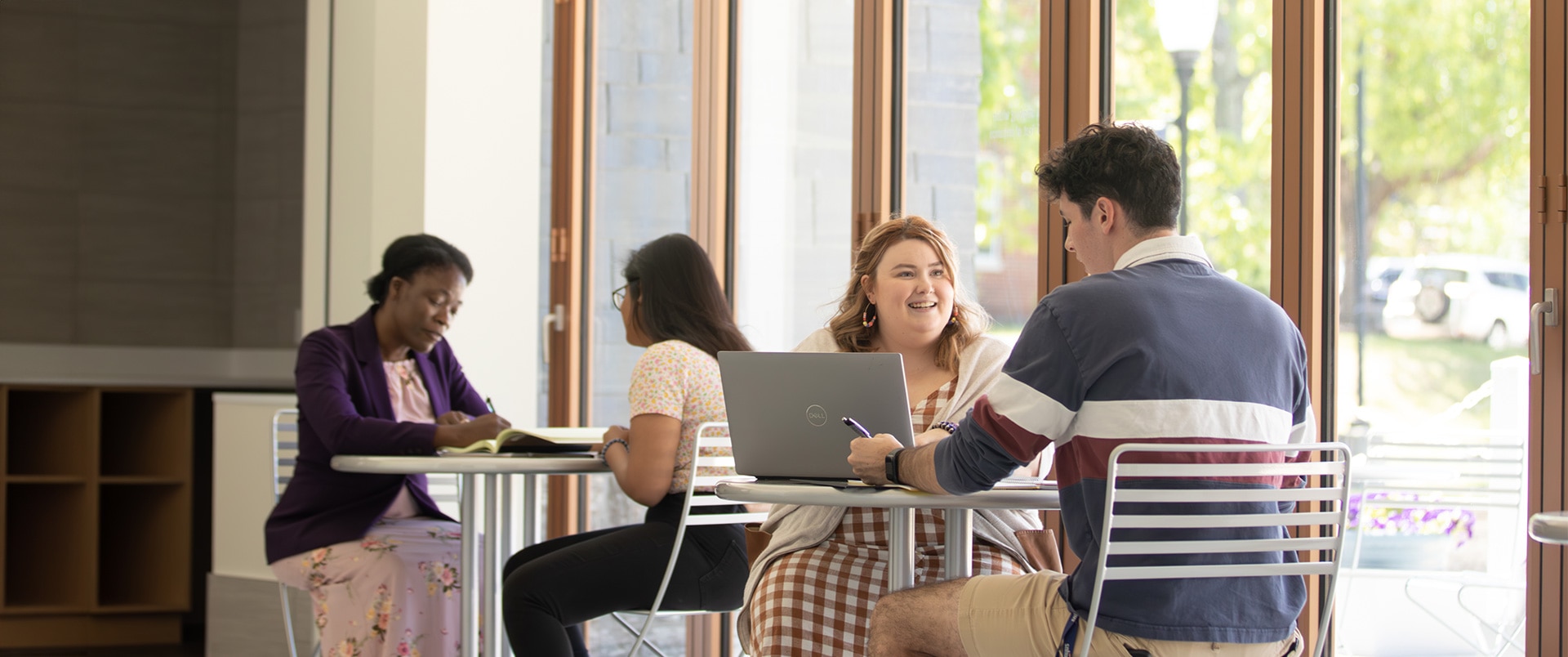 Two groups of students sitting at two sets of tables studying together.