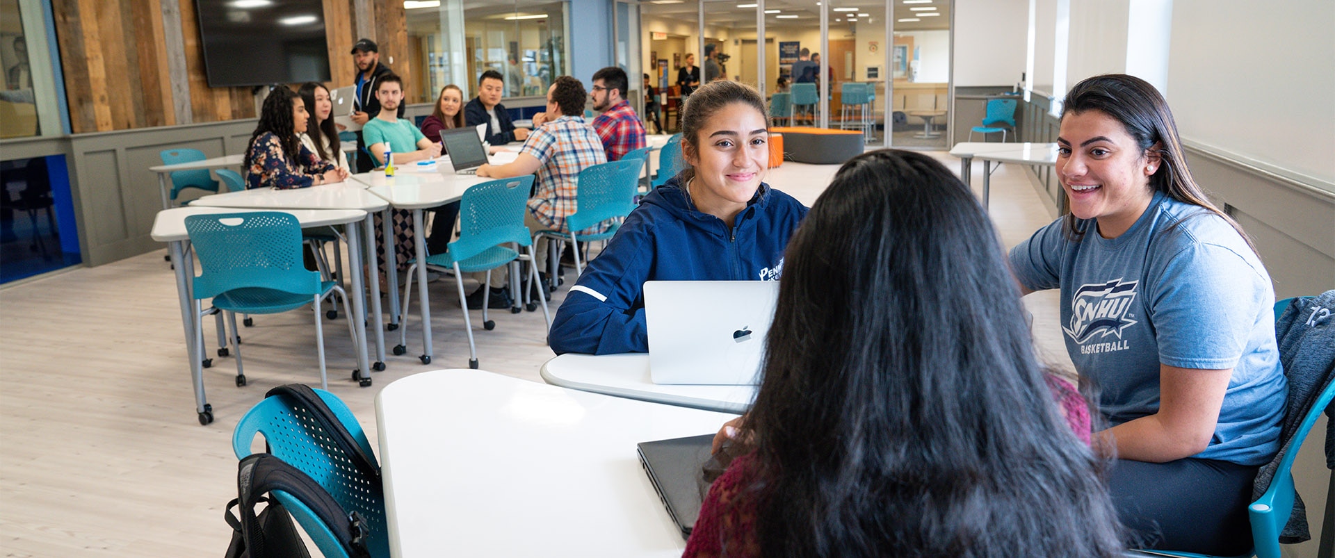 Two groups of students sitting at desks and collaborating in a classroom environment.