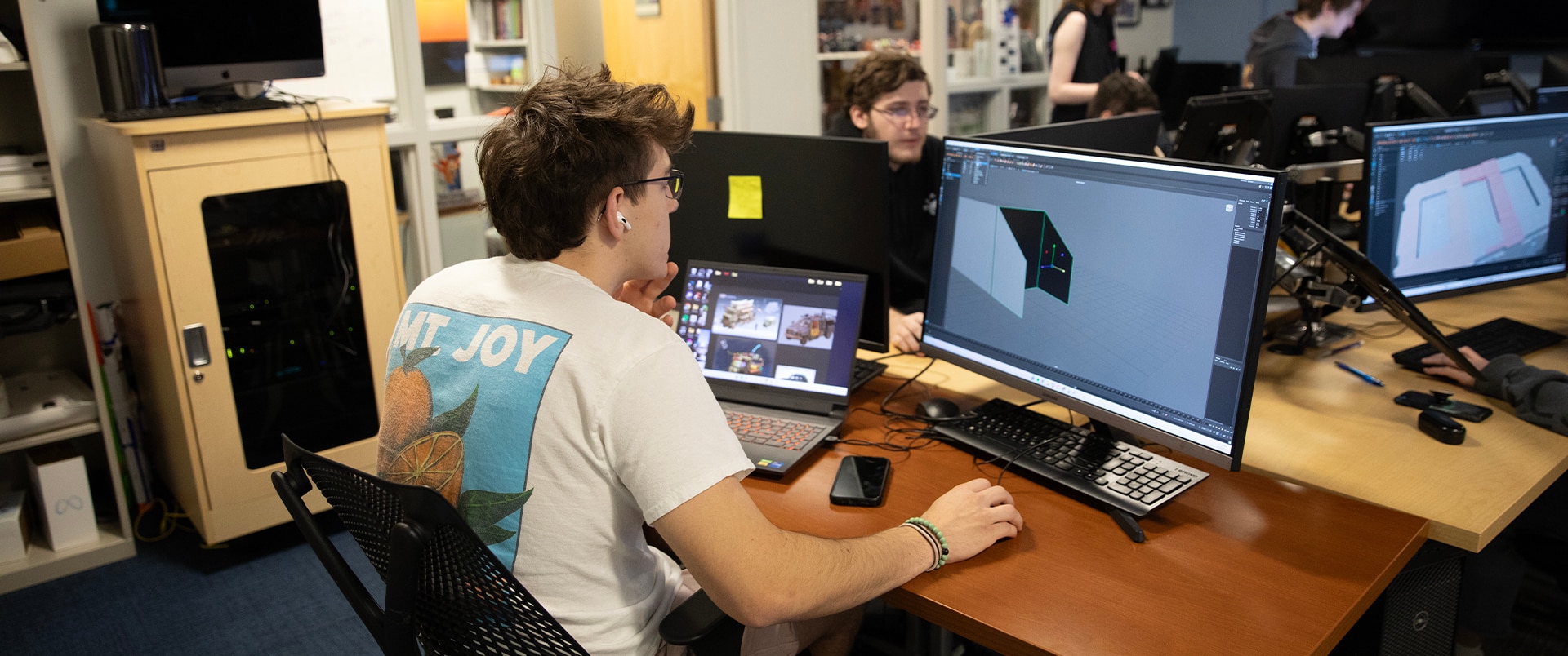 A group of students working on computer graphics and design in a classroom setting.