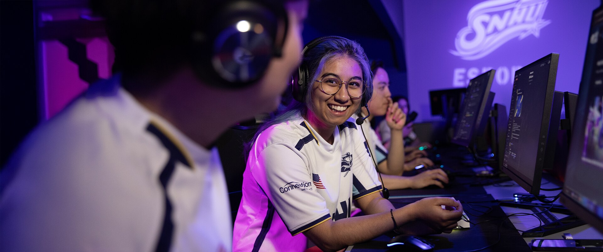 Students smiling while playing games at SNHU esports arena.