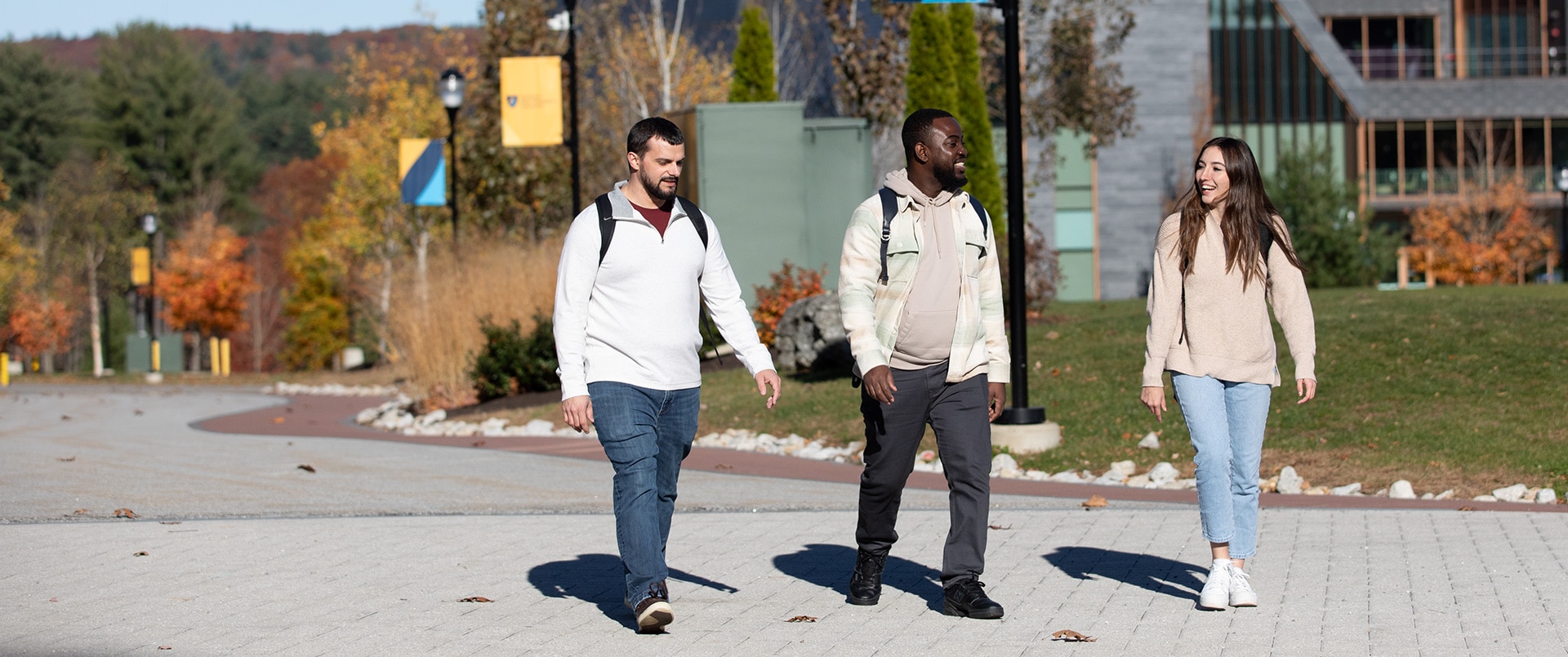 Three students conversing with each other while taking a walk on campus.