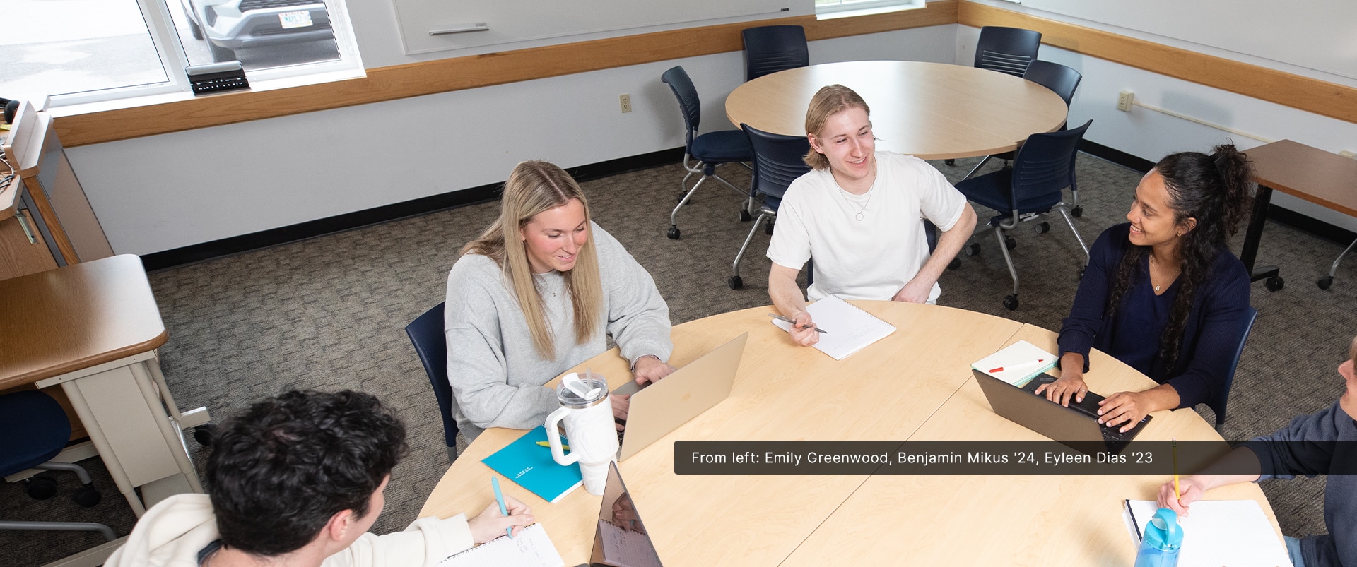 Two campus students sitting and studying together while smiling.