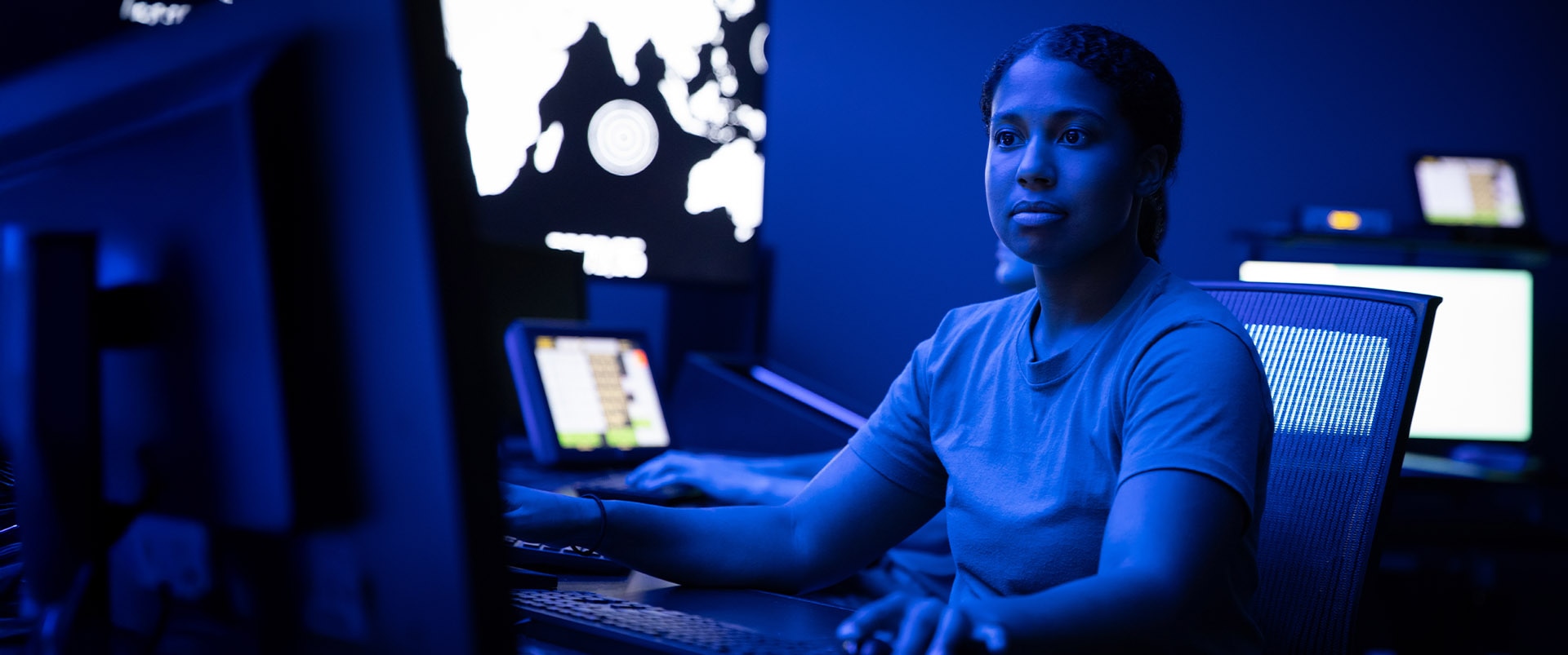 A woman typing on a computer in a dimly lit office.