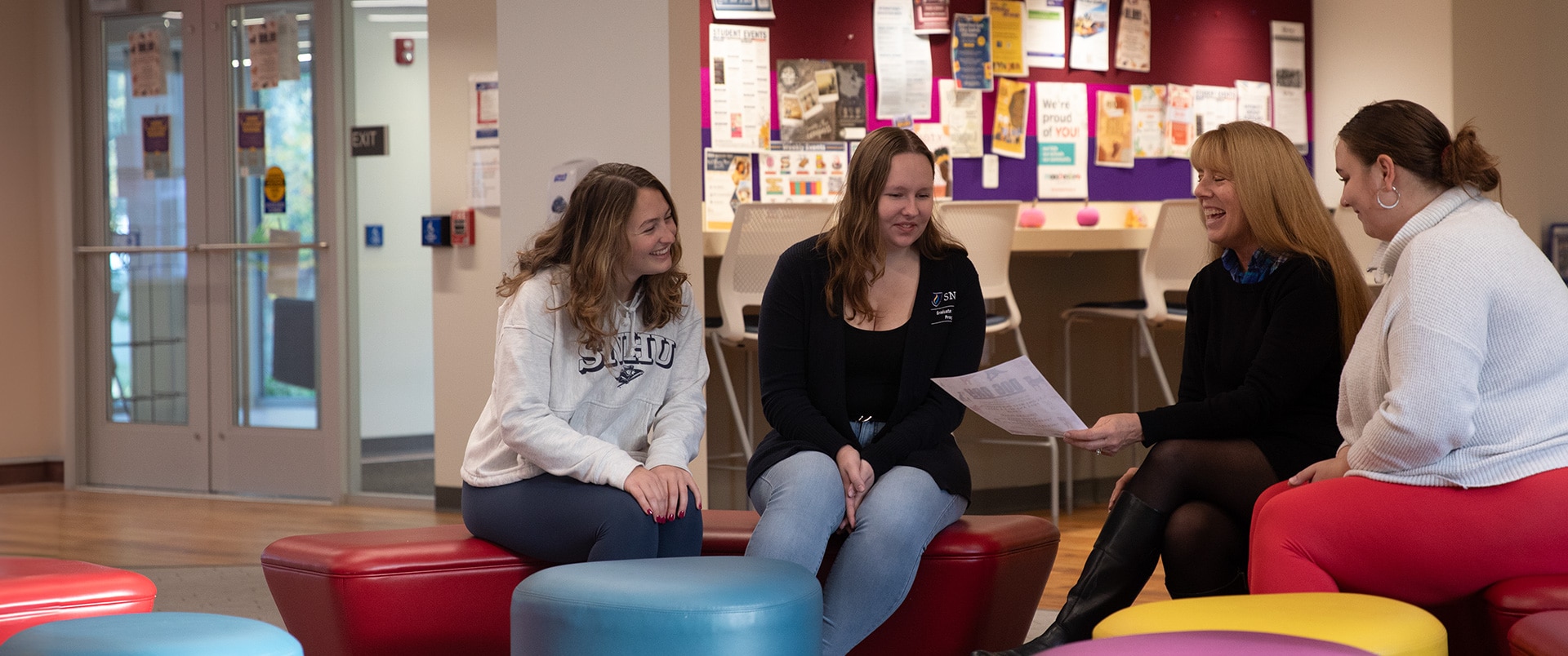A group of four women looking into a paper, engaged in conversation.