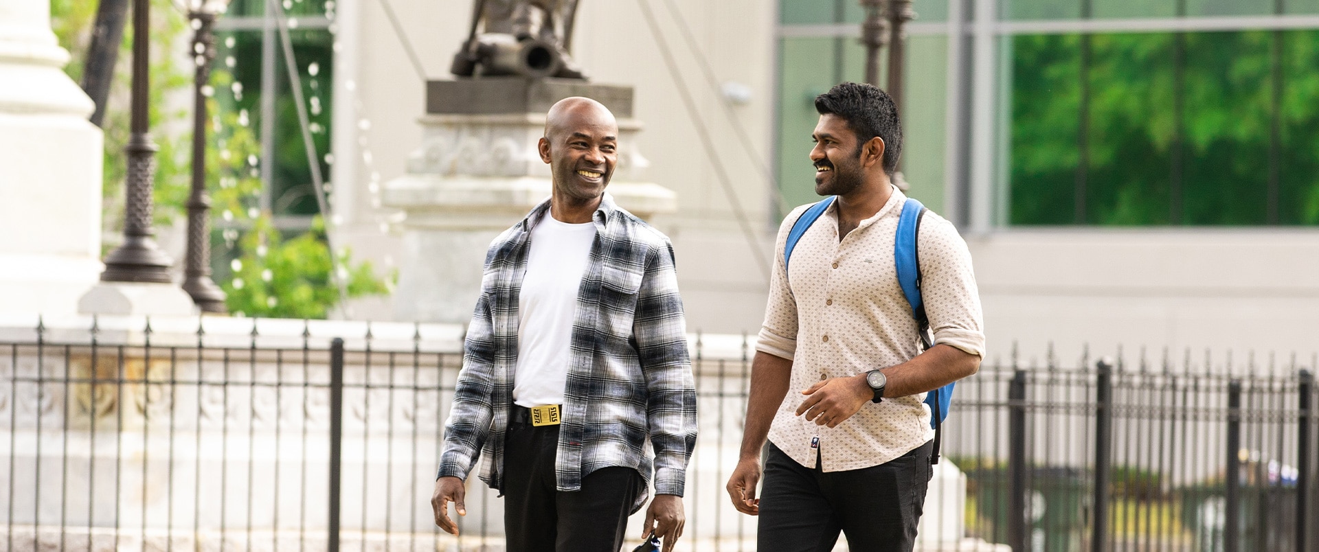 Two individuals talking and walking outside a building.
