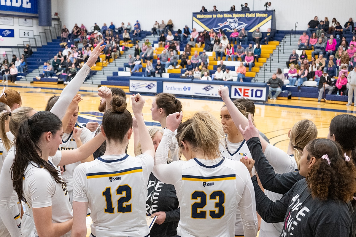 SNHU women's basketball team in a team huddle.