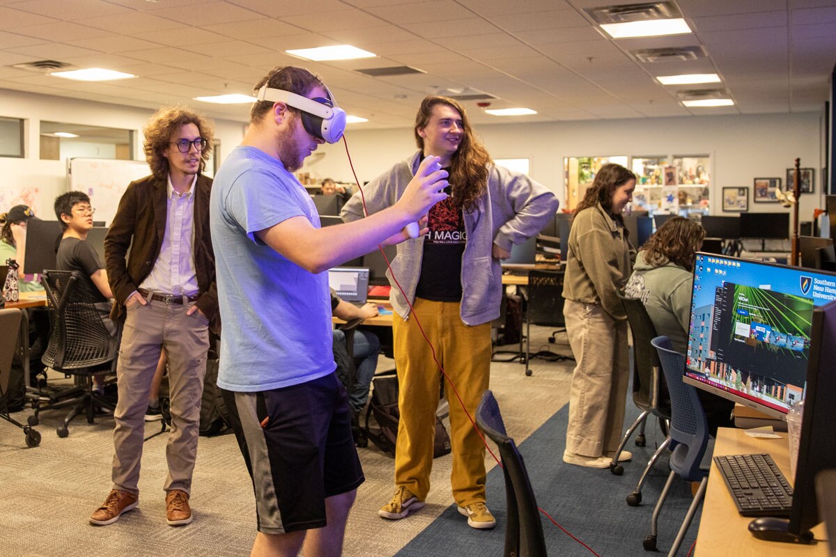 Three students working on a VR game in the Inkwell Interactive Studio with others working in the background.