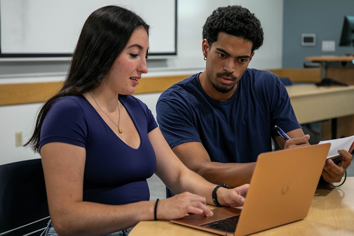 Two students working together on a laptop.